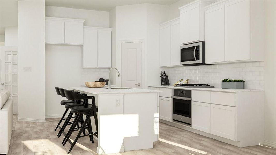 Kitchen with a center island with sink, appliances with stainless steel finishes, white cabinetry, light wood-type flooring, and sink