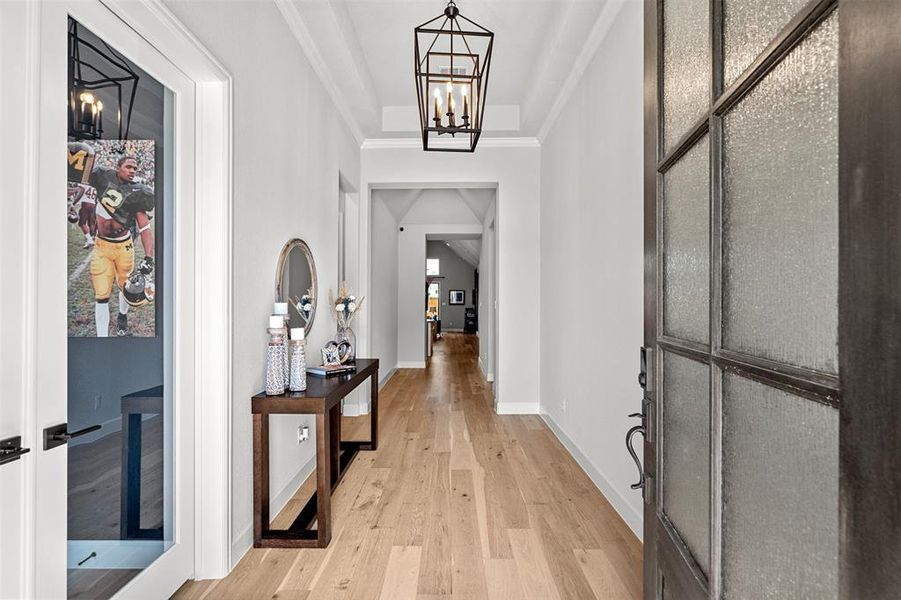 Hall with ornamental molding, light hardwood / wood-style flooring, and a chandelier