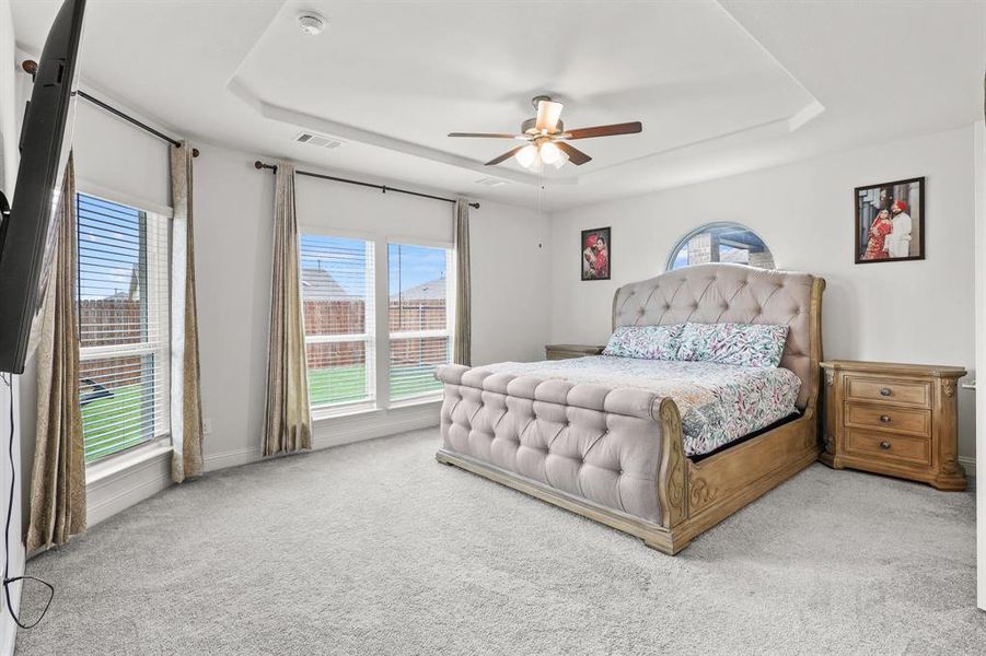 Bedroom featuring a raised ceiling, carpet flooring, and ceiling fan