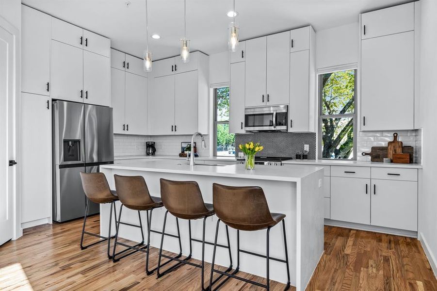 Kitchen featuring an island, plenty of natural light, stainless steel appliances, and white cabinets