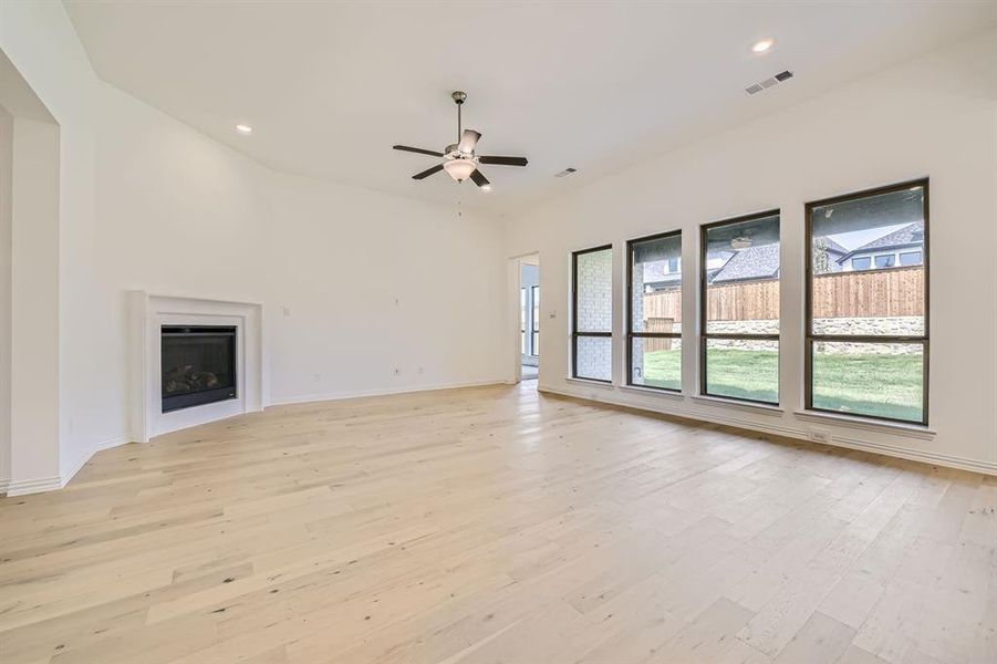 Unfurnished living room featuring ceiling fan, lofted ceiling, and light hardwood / wood-style floors