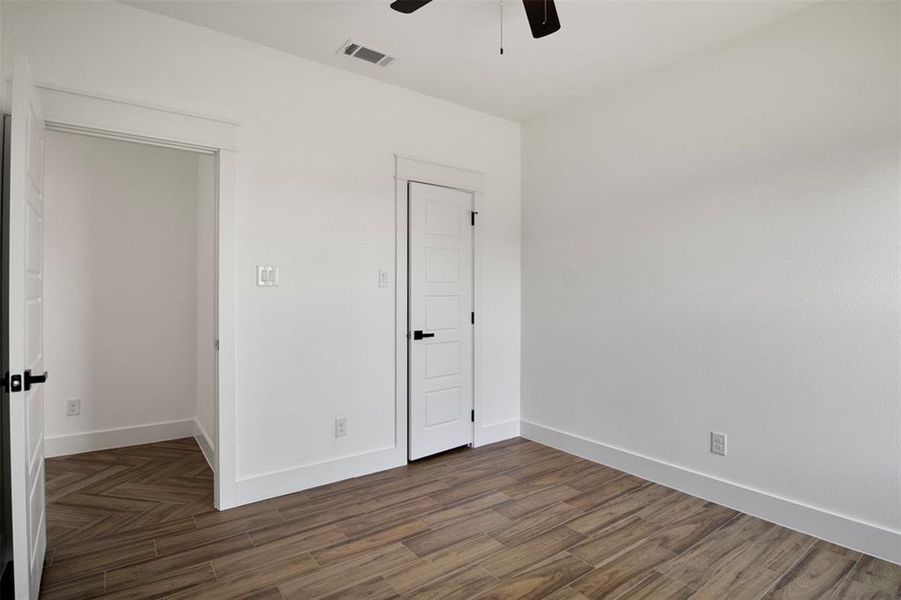 Unfurnished bedroom with ceiling fan and dark wood-type flooring