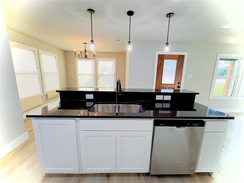 Kitchen featuring white cabinets, an island with sink, and stainless steel dishwasher