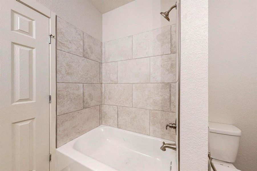 Bathroom featuring toilet and tiled shower / bath combo