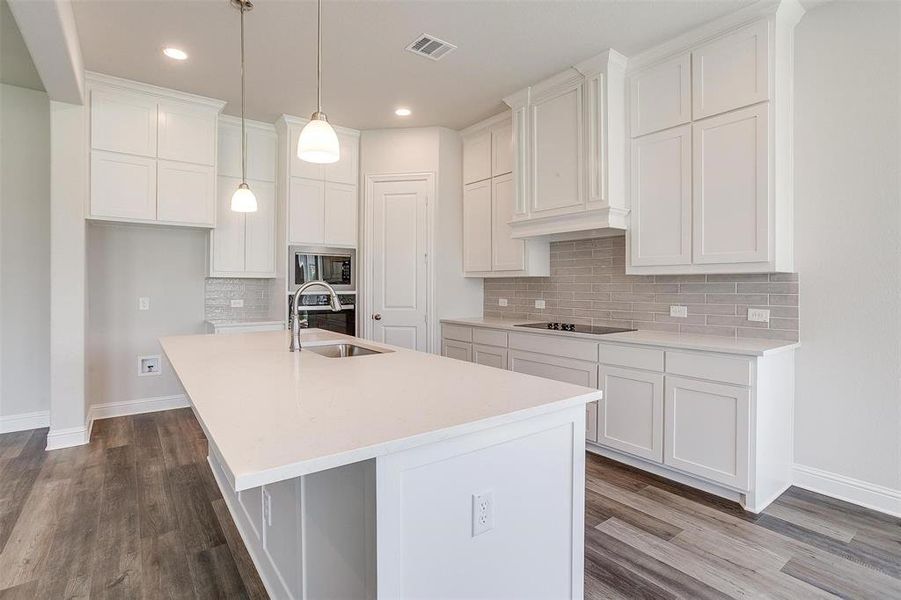 Kitchen with sink, a center island with sink, backsplash, and hardwood / wood-style floors