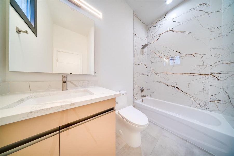 Full bathroom with vanity, tiled shower / bath, and toilet