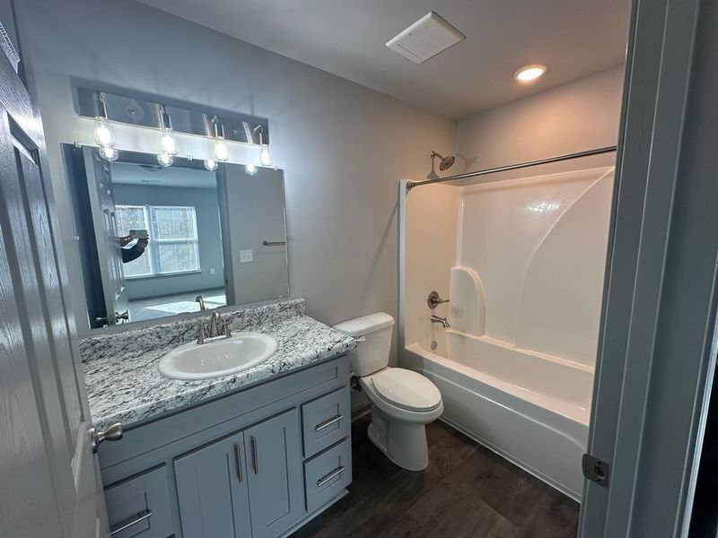 Full bathroom with bathing tub / shower combination, toilet, oversized vanity, and hardwood / wood-style flooring