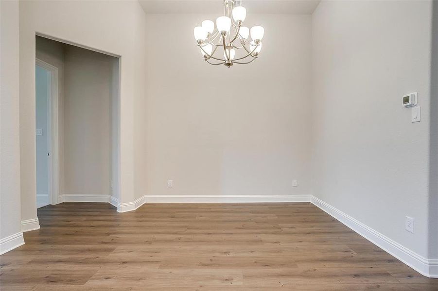 Spare room featuring hardwood / wood-style flooring and a notable chandelier