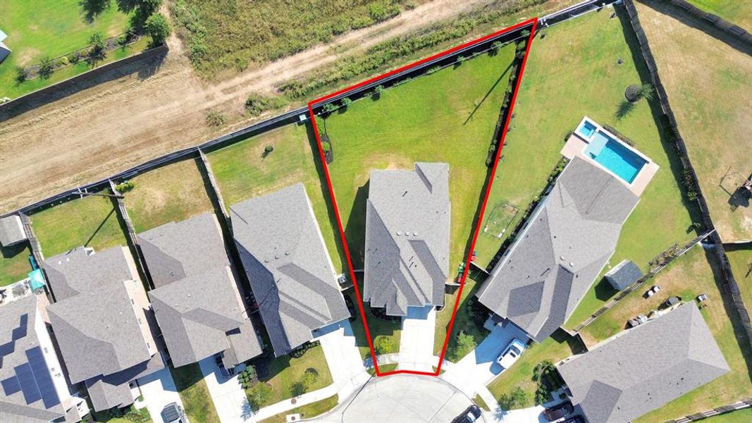 This aerial image outlines a sizable, rectangular residential lot with clear boundaries marked in red. The property is nestled within a suburban neighborhood, flanked by houses with well-maintained yards, and features open space suitable for potential landscaping or outdoor amenities.