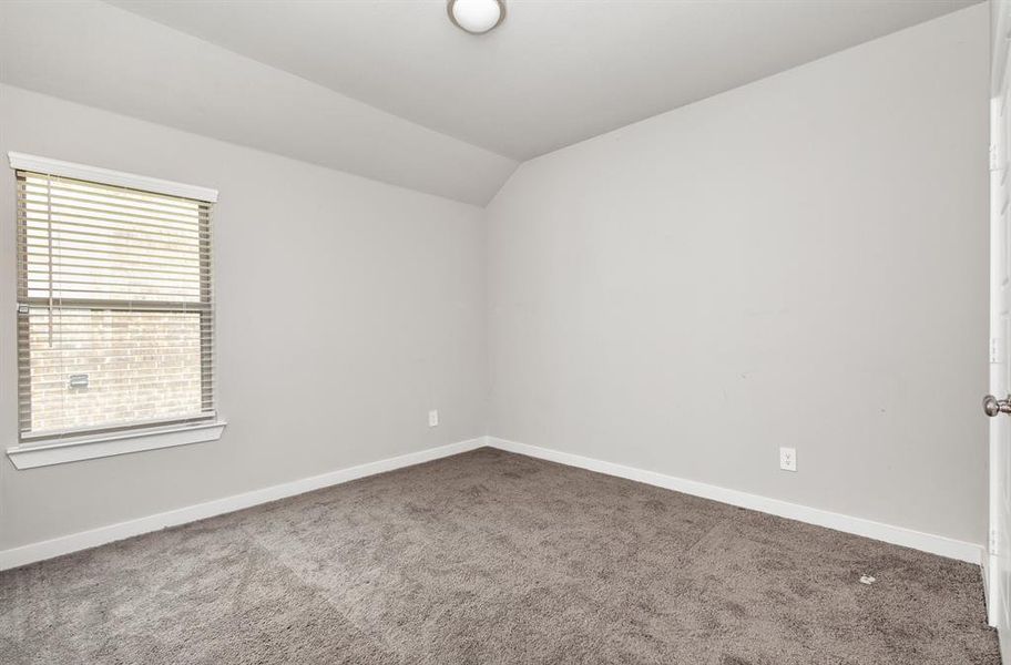 Carpeted spare room with vaulted ceiling