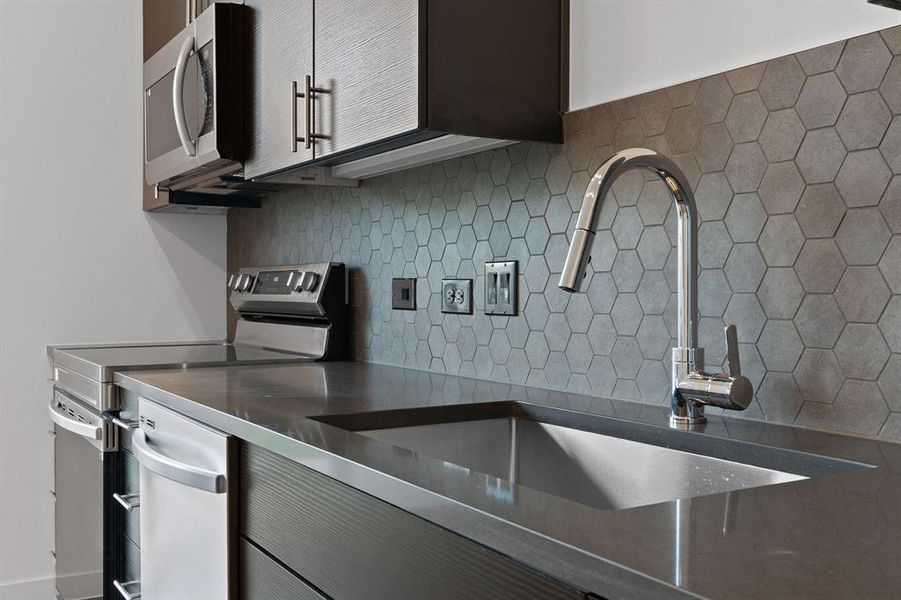 Sleek quartz counters with stainless undermount sink.