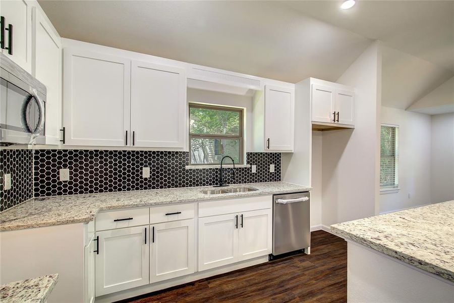 Kitchen featuring light stone countertops, stainless steel appliances, white cabinets, dark hardwood / wood-style floors, and backsplash