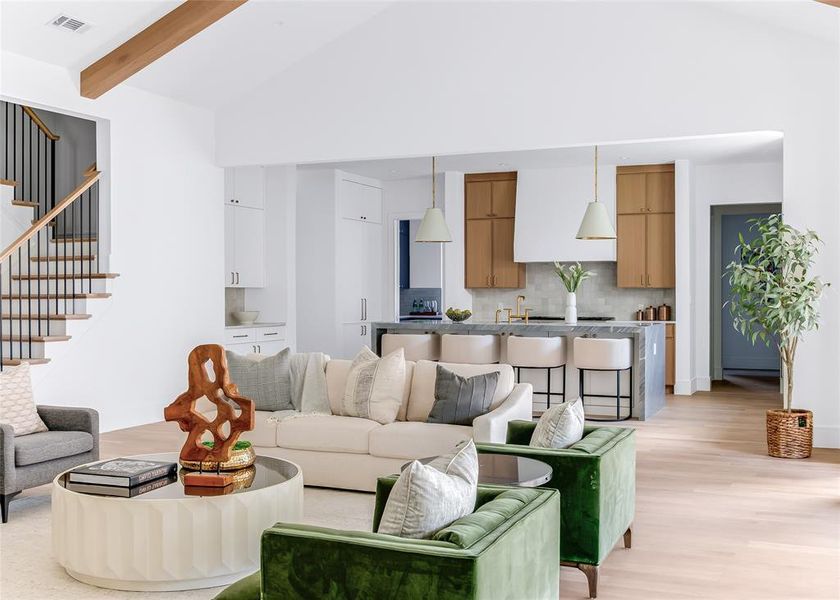 Living room with light hardwood / wood-style floors, beamed ceiling, and high vaulted ceiling