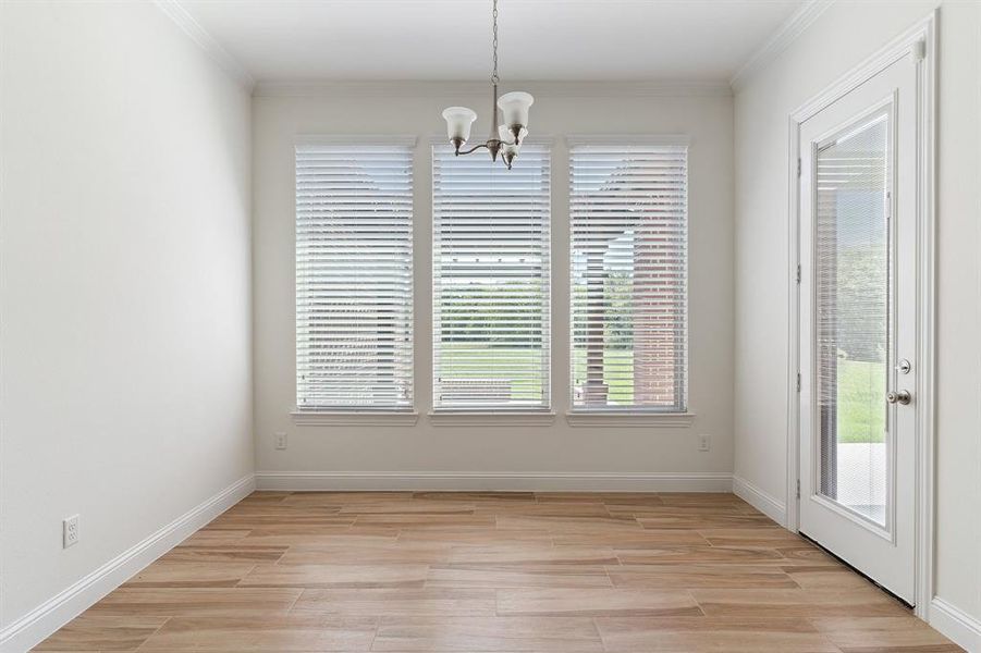 Unfurnished dining area featuring light hardwood / wood-style floors, a chandelier, and ornamental molding