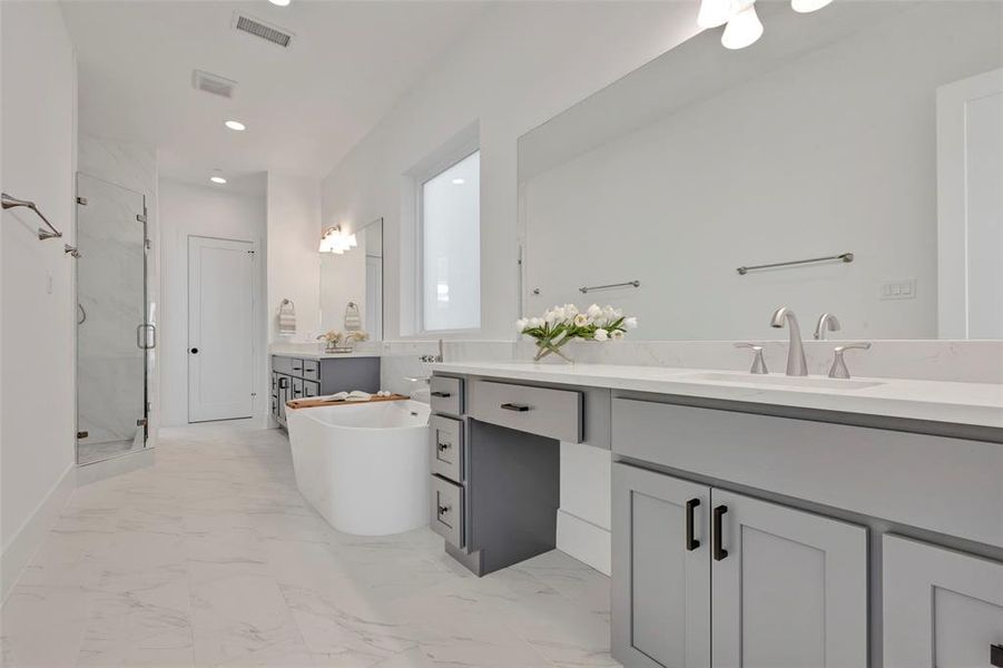 The primary bathroom boasts double vanities (one with a seating area), a relaxing soaking tub, and a glass-enclosed separate shower. The closed door is the walk-in-closet.