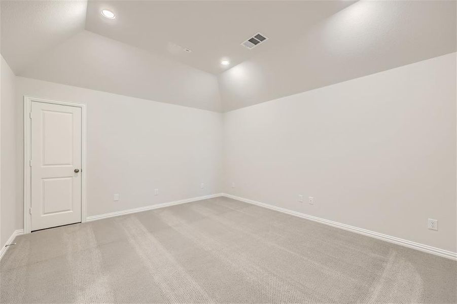 Carpeted empty room featuring lofted ceiling