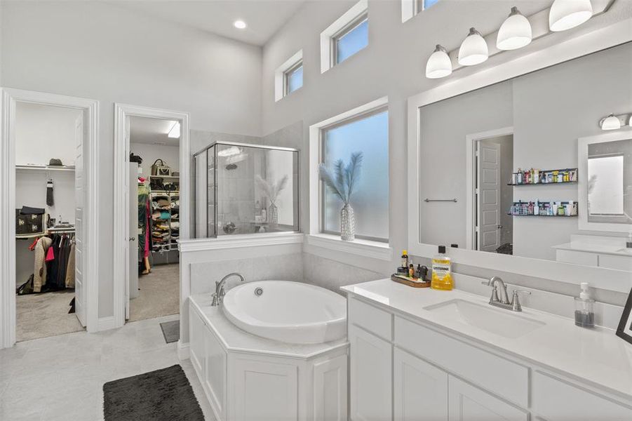 Bathroom featuring vanity, a towering ceiling, separate shower and tub, and tile patterned floors