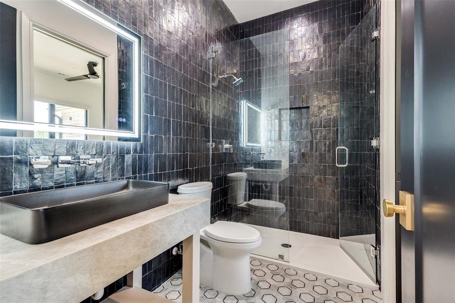 Bathroom with tile walls, ceiling fan, toilet, tile floors, and walk in shower