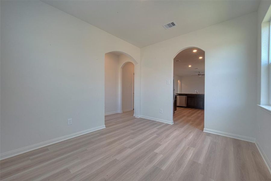 Room with wood flooring and arched doorways leading to other rooms. Clean, modern interior,  in a house.