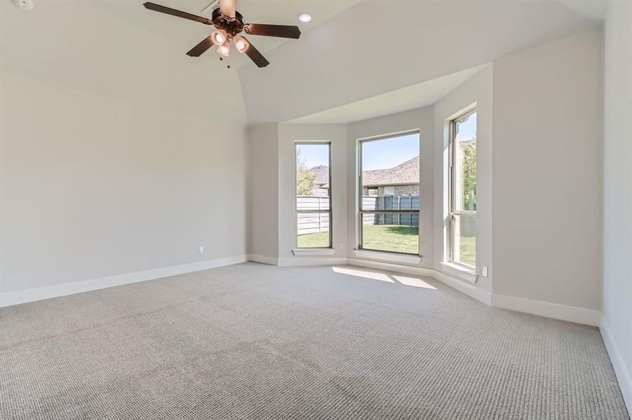 Spare room featuring ceiling fan, high vaulted ceiling, and light colored carpet