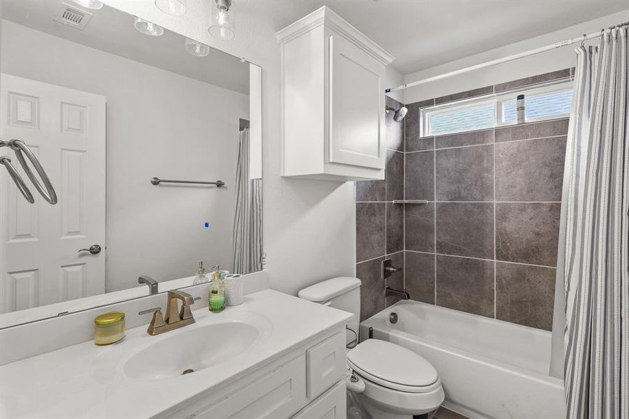 Full bathroom featuring vanity, toilet, and shower / bath combination with curtain