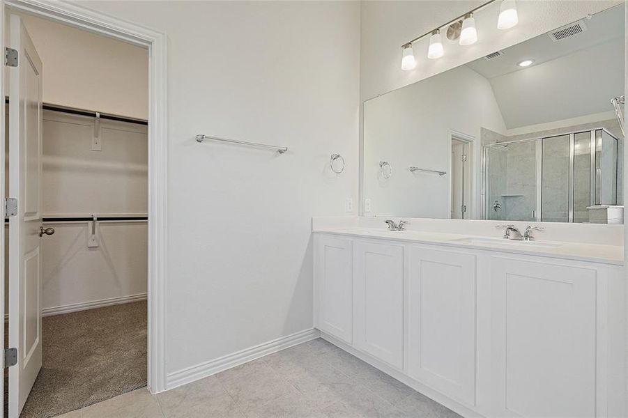 Bathroom with vanity, tile patterned floors, walk in shower, and lofted ceiling