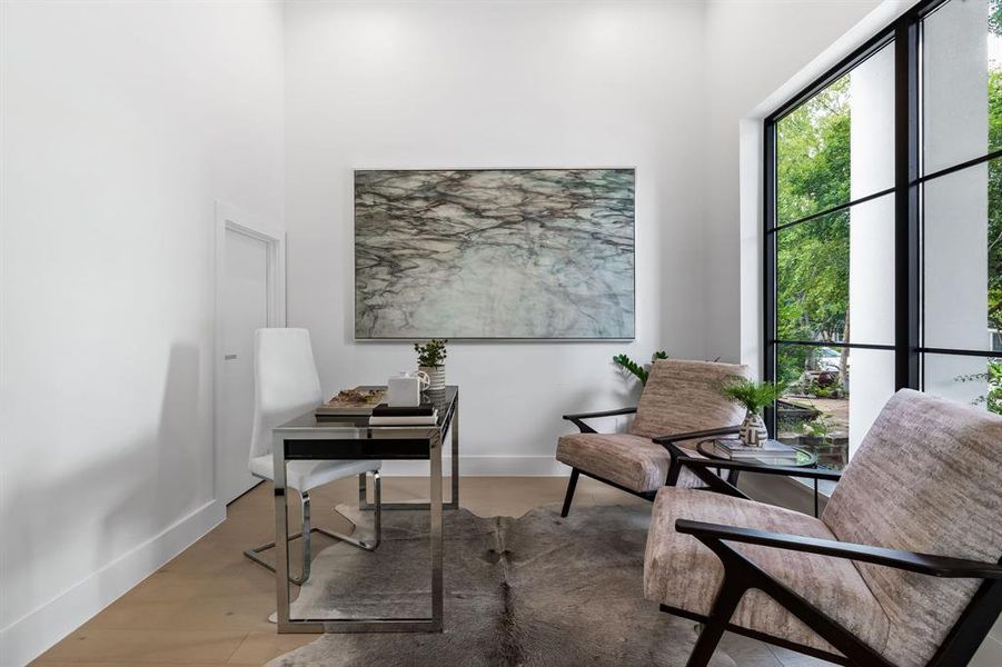 Office space featuring light hardwood / wood-style flooring and a towering ceiling