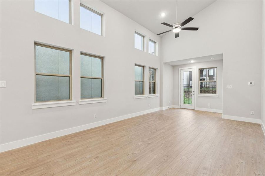 Unfurnished room with high vaulted ceiling, ceiling fan, a wealth of natural light, and light hardwood / wood-style floors