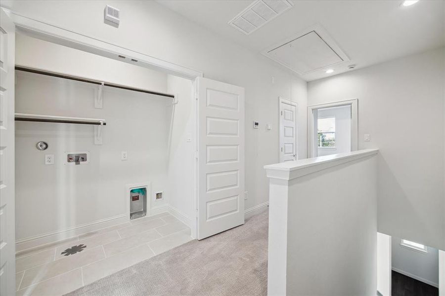 The laundry area offers practicality and convenience with ample space for full-sized appliances and built-in shelving for organization. Located steps from the bedrooms, it ensures easy access for everyday tasks while maintaining a sleek and modern look. Perfect for managing household chores efficiently.