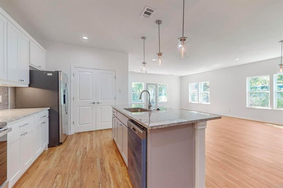 Un-staged Kitchen featuring an island with sink, stainless steel appliances, sink, and a healthy amount of sunlight