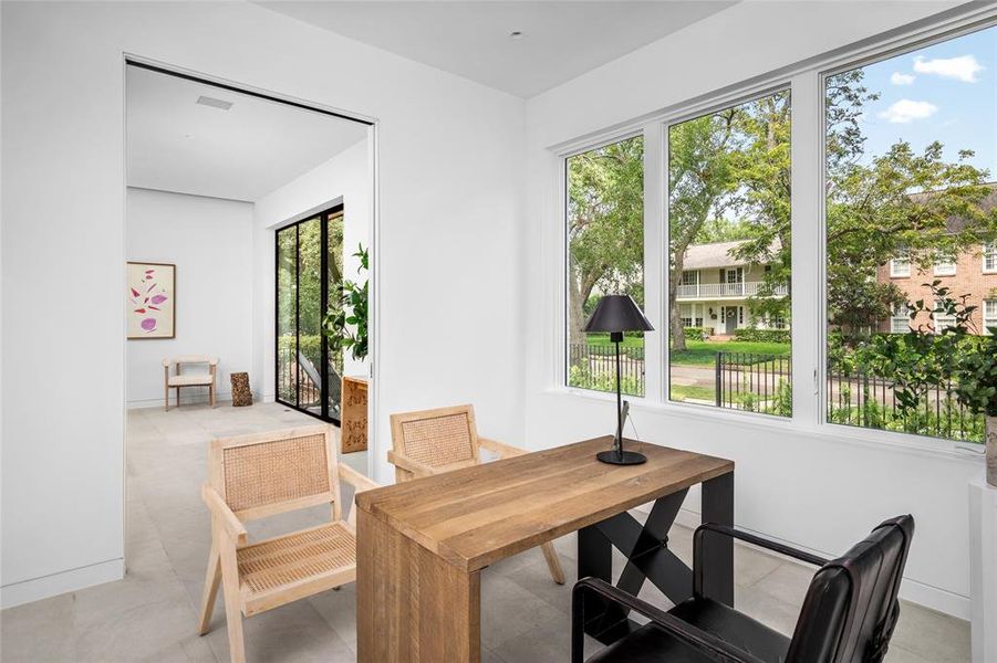 The study offers seamless access to the foyer through convenient pocket doors and features sleek, clean lines that contribute to the home's modern aesthetic. The Moroccan limestone flooring flows throughout, perfectly complementing the large windows that flood the room with natural light and offer beautiful views of the tree-lined street.