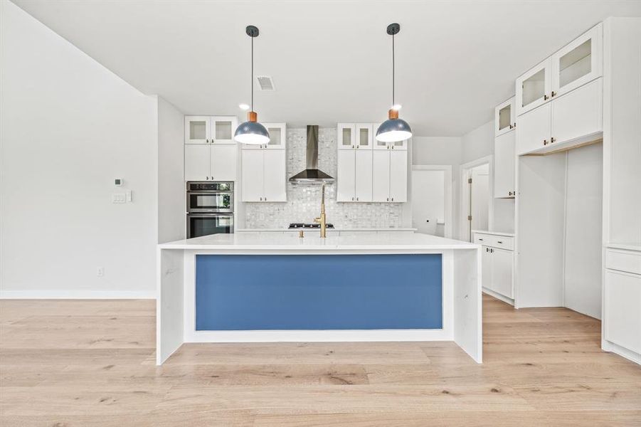 Kitchen with stainless steel appliances, wall chimney exhaust hood, and white cabinets