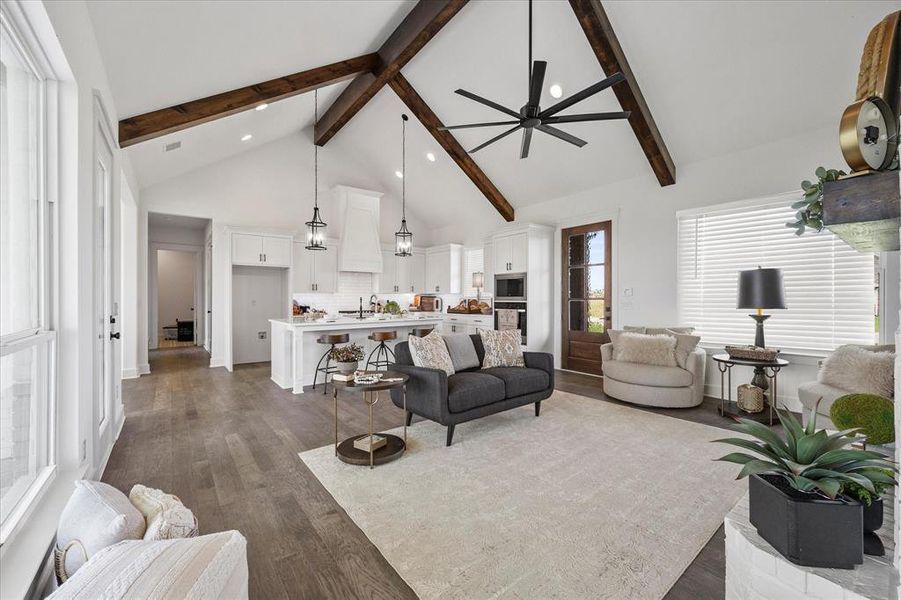 Living room featuring high vaulted ceiling, beamed ceiling, ceiling fan, wood-type flooring, and sink