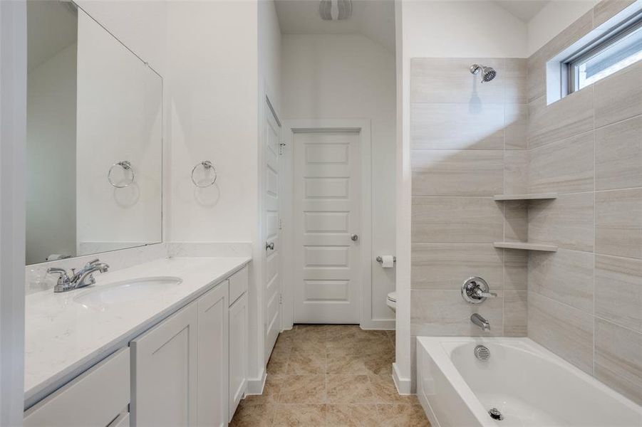 Full bathroom featuring tiled shower / bath combo, vanity, tile patterned floors, and toilet