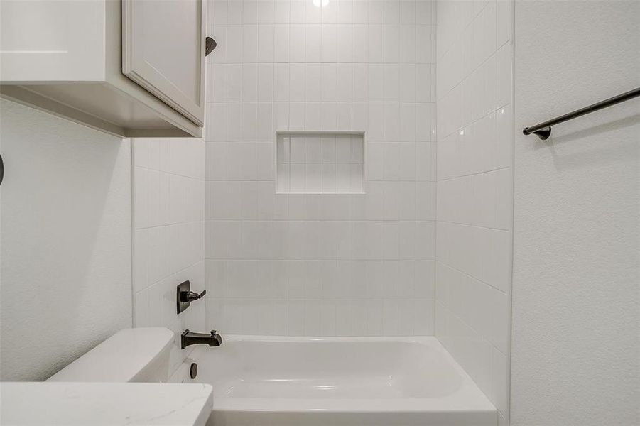 Bathroom with toilet and tiled shower / bath combo