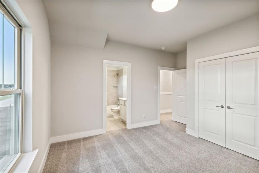 Unfurnished bedroom with ensuite bath, light colored carpet, and a closet