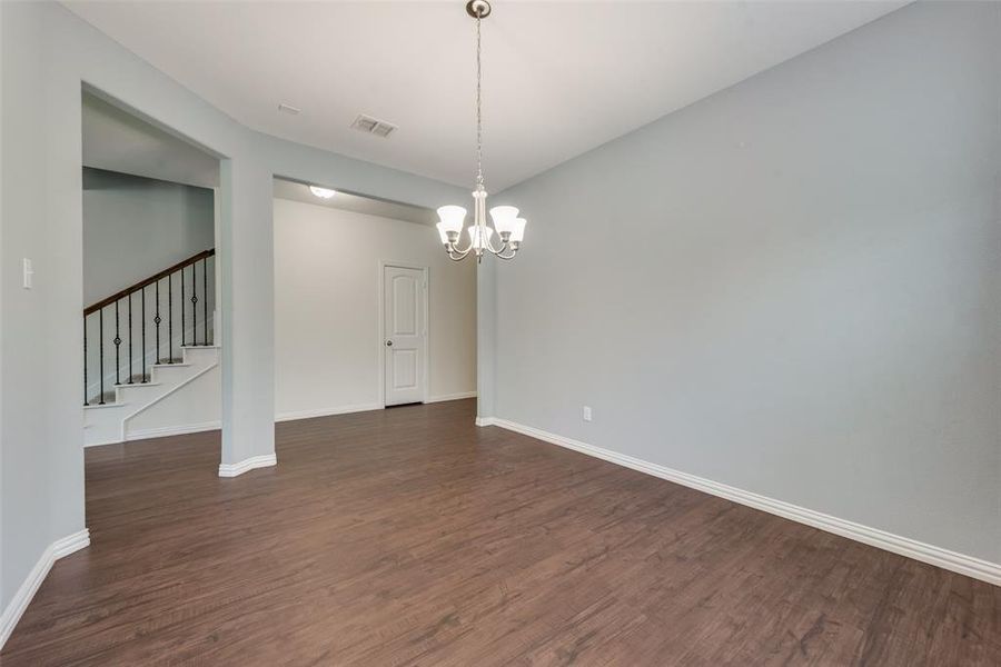 Empty room with a notable chandelier and dark hardwood / wood-style flooring