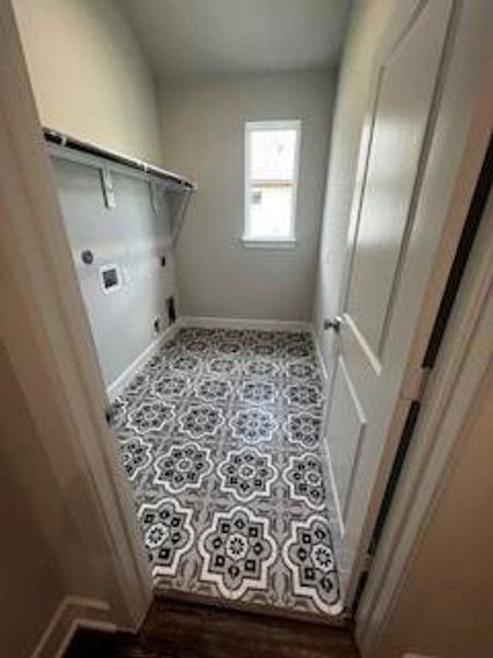 Laundry room features beautiful designer tile and built in shelving.