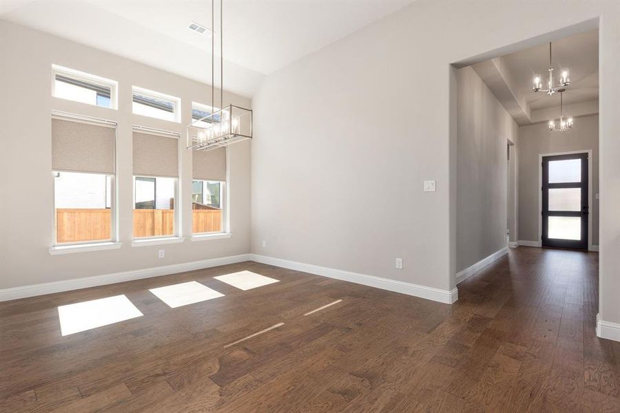 Unfurnished dining area featuring a notable chandelier and dark hardwood / wood-style flooring