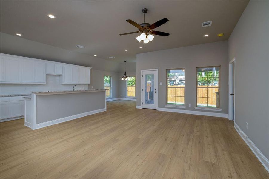 Unfurnished living room with sink, ceiling fan, and light hardwood / wood-style floors