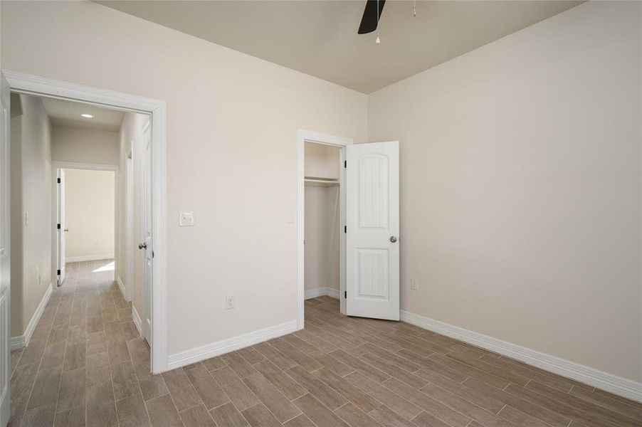 Unfurnished bedroom with a closet, light hardwood / wood-style floors, a walk in closet, and ceiling fan