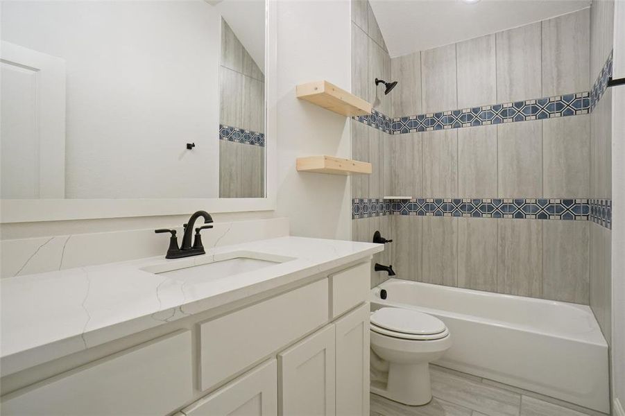 Full bathroom featuring toilet, vanity, and tiled shower / bath