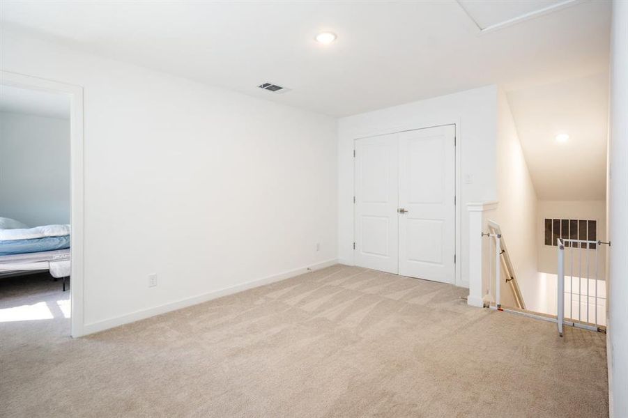 Unfurnished bedroom with a closet, light carpet, and lofted ceiling