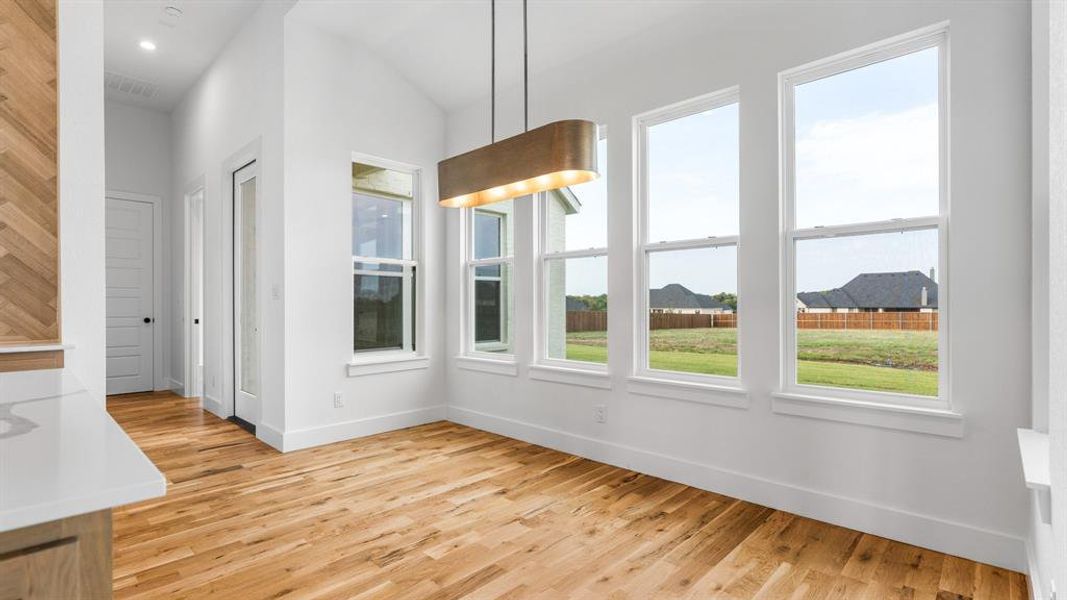 Unfurnished dining area with lofted ceiling and light hardwood / wood-style floors