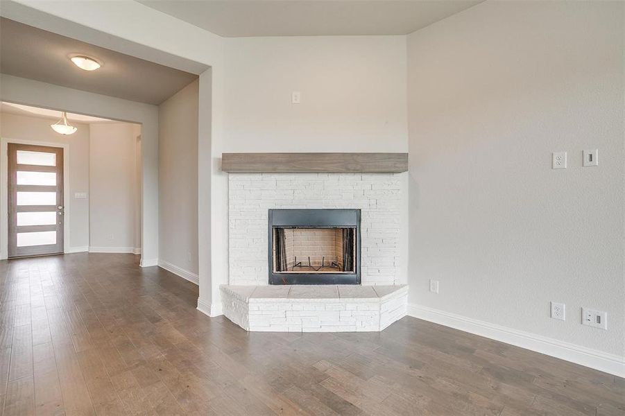 Unfurnished living room featuring a stone fireplace and dark hardwood / wood-style flooring