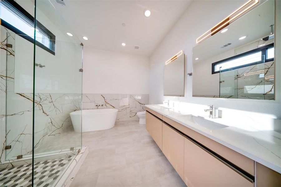 Full bathroom featuring vanity, shower with separate bathtub, toilet, and tile walls