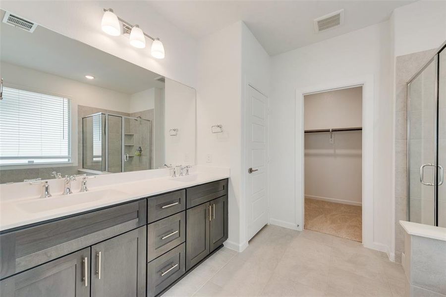 Bathroom with tile patterned flooring, a shower with door, and vanity