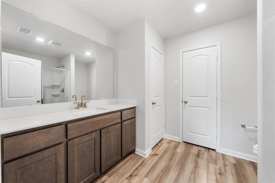 Bathroom with vanity, toilet, hardwood / wood-style floors, and a shower with shower door