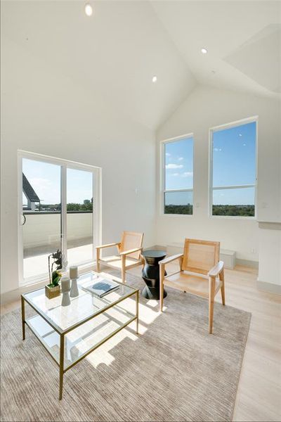 Living room with light hardwood / wood-style flooring, high vaulted ceiling, and a wealth of natural light