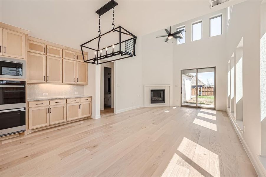 Kitchen featuring pendant lighting, light hardwood / wood-style flooring, a towering ceiling, built in microwave, and ceiling fan